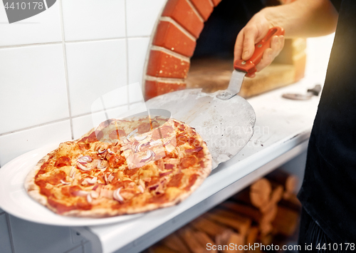 Image of chef placing pizza from peel to plate at pizzeria