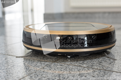 Image of Robotic vacuum cleaner on bright marble floor