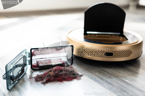 Image of robotic vacuum cleaner on wood floor with emptied dirt container