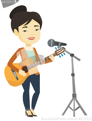 Image of Woman singing in microphone and playing guitar.