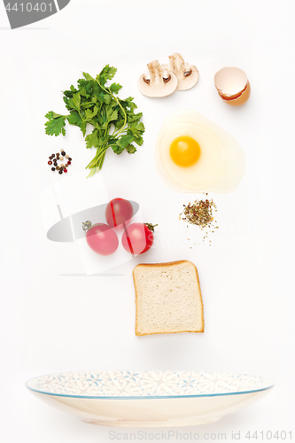 Image of The falling ingredients of fried egg. Healthy breakfast ingredients.