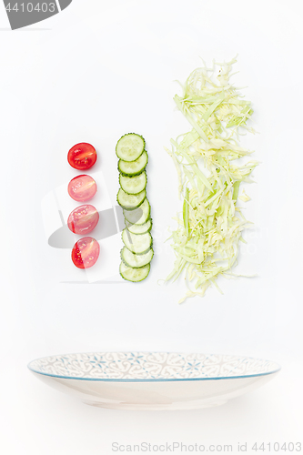 Image of The salad bowl in flight with vegetables: tomato, cucumber, cabbage on white background
