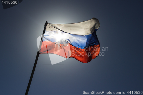 Image of russian flag flying in slow motion and back lit by the sun.