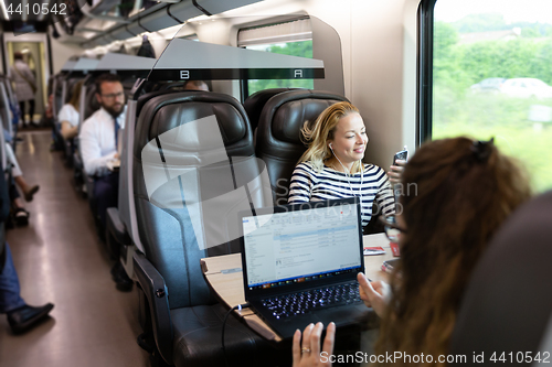 Image of Businesswoman communicating on mobile phone while traveling by train.