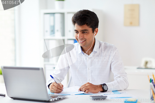 Image of businessman in earphones working at office