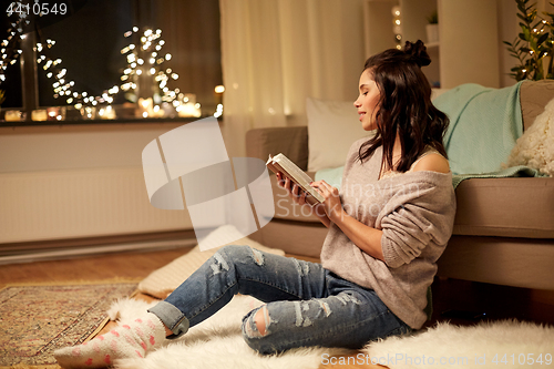 Image of happy young woman reading book at home