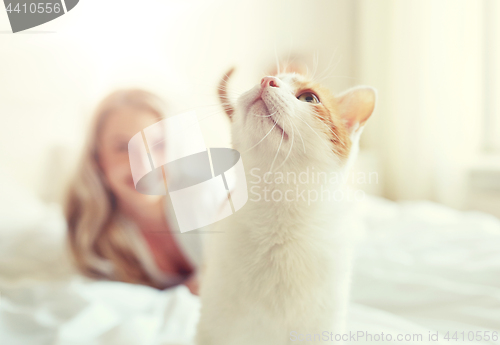 Image of happy young woman with cat in bed at home