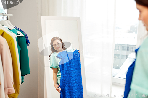 Image of pensive plus size woman with blue dress at mirror