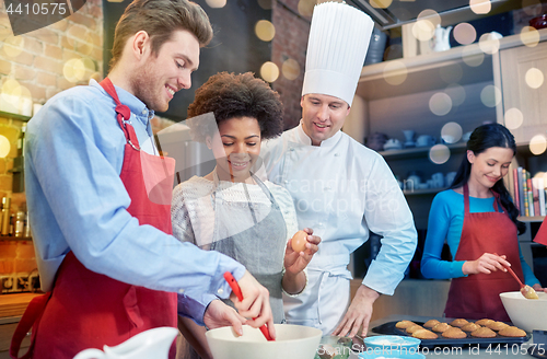 Image of happy friends and chef cook baking in kitchen