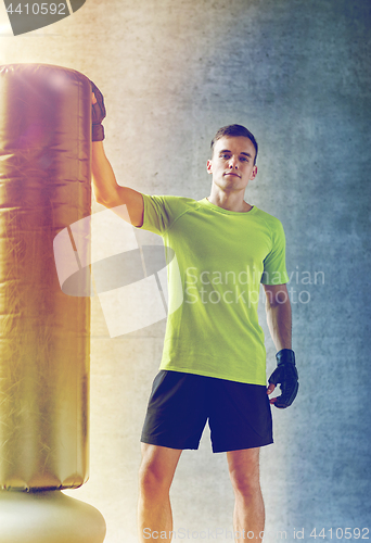 Image of man with boxing gloves and punching bag in gym