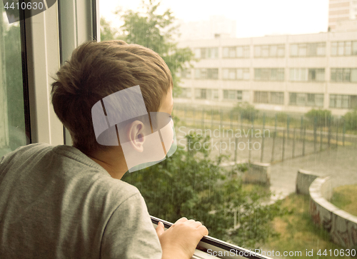 Image of Boy watching the rain through the window