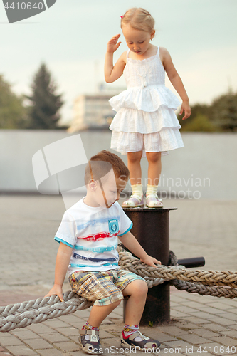 Image of Happy family brother and sister playing on the embankment