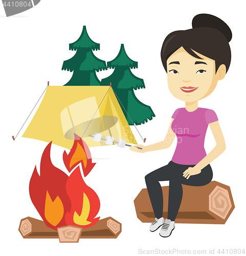 Image of Woman roasting marshmallow over campfire.