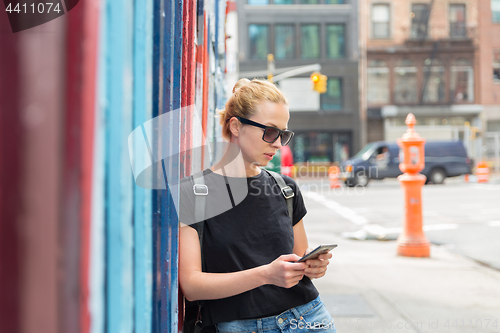 Image of Woman using smartphones against colorful graffiti wall in New York city, USA.