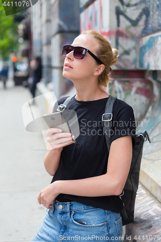 Image of Woman using smartphones against colorful graffiti wall in New York city, USA.