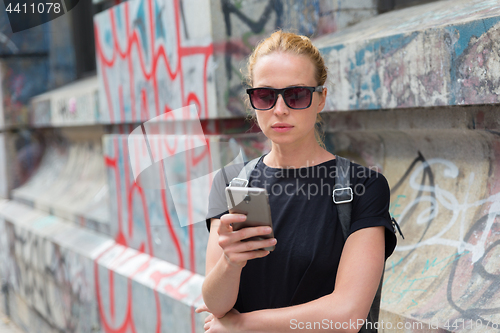 Image of Woman using smartphones against colorful graffiti wall in New York city, USA.