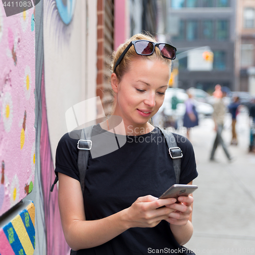 Image of Woman using smartphones against colorful graffiti wall in New York city, USA.