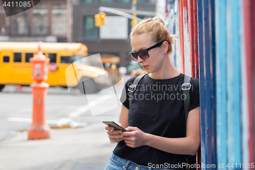 Image of Woman using smartphones against colorful graffiti wall in New York city, USA.