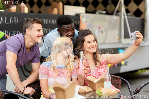 Image of happy young friends taking selfie at food truck