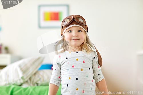 Image of happy little girl in pilot hat playing at home