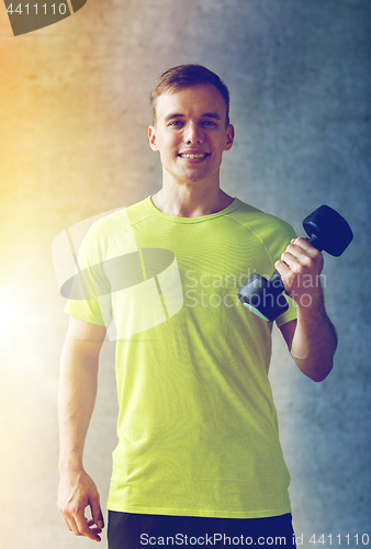 Image of smiling man with dumbbell in gym