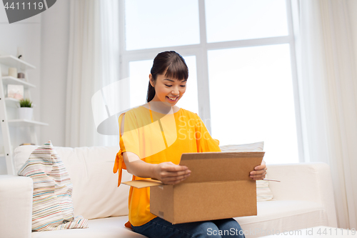 Image of happy asian young woman with parcel box at home