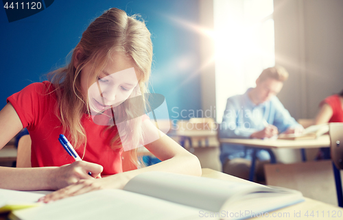 Image of student girl with book writing school test