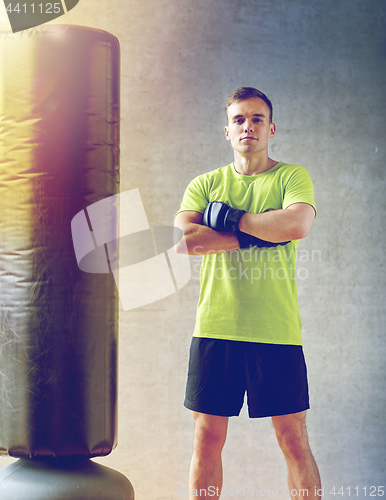 Image of man with boxing gloves and punching bag in gym