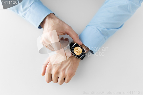 Image of close up of hands with bitcoin on smart watch