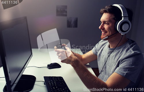 Image of man in headset playing computer video game at home