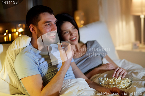 Image of couple with popcorn watching tv at night at home