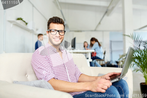 Image of man in eyeglasses with laptop working at office