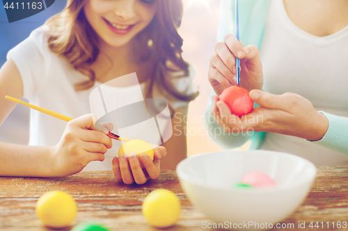 Image of daughter and mother coloring easter eggs