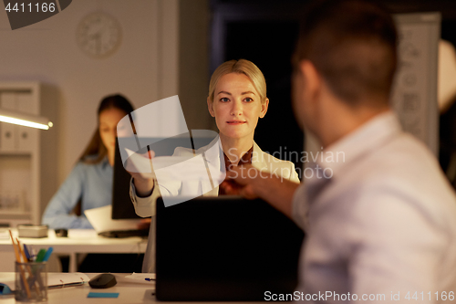 Image of coworkers with papers working late at night office