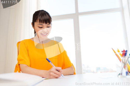 Image of happy student girl with book and notebook at home