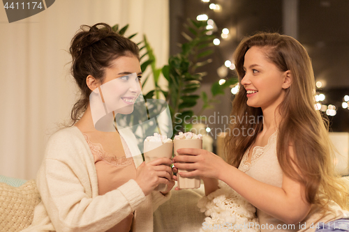 Image of happy female friends drinking cacao at home