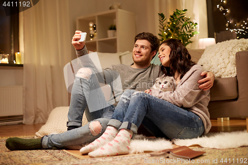 Image of happy couple taking selfie by smartphone at home