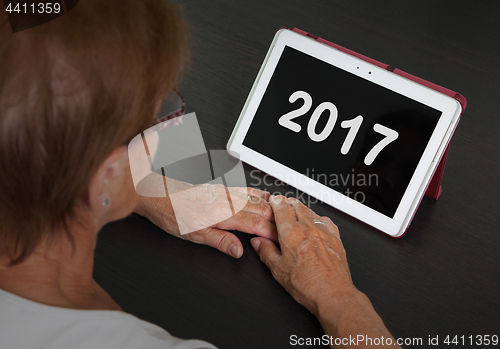 Image of Senior lady relaxing and her tablet - 2017