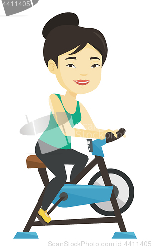 Image of Young woman riding stationary bicycle.