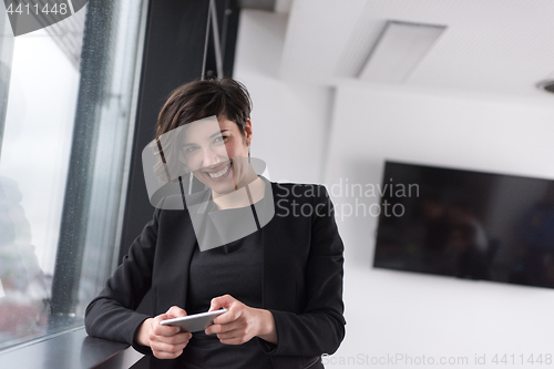 Image of Elegant Woman Using Mobile Phone by window in office building