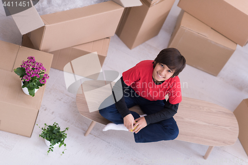 Image of boy sitting on the table with cardboard boxes around him top vie