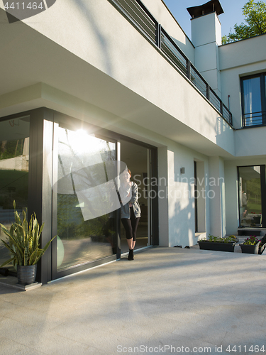 Image of woman drinking coffee in front of her luxury home villa