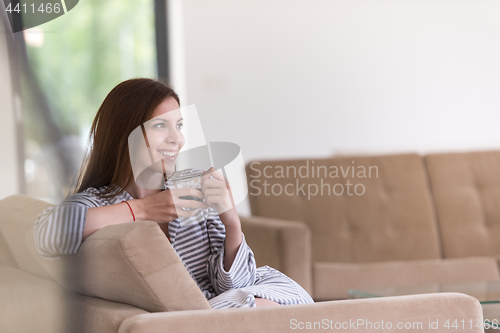 Image of young woman in a bathrobe enjoying morning coffee