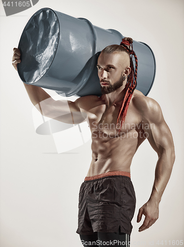 Image of Fitness man with perfect body doing exercises with iron barrel