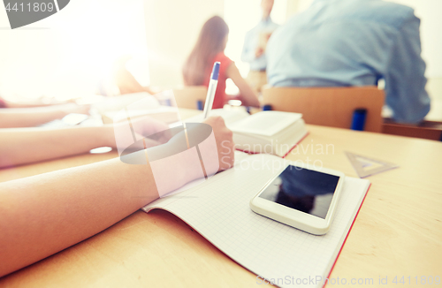 Image of student with smartphone and notebook at school