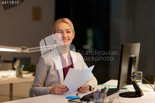 Image of businesswoman with papers working at night office