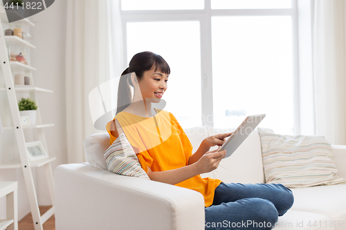 Image of happy young asian woman with tablet pc at home