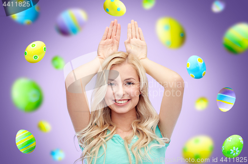 Image of happy woman making bunny ears over easter eggs