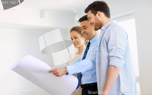 Image of realtor showing blueprint of new home to couple