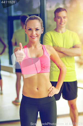 Image of smiling man and woman showing thumbs up in gym